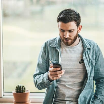 man holding a smartphone near the window